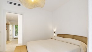 A bedroom with a bed, a bench, a wall-mounted light, and a door leading to a balcony. - GuestHost - 68 sqm apartment for 2 people, featuring 3 balconies with a stunning sea view. Centrally located in Taormina, it offers the convenience of being close to all major attractions while remaining quiet and peaceful. Ideal for a couple seeking rel (Taormina)
