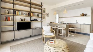 A modern living room with a TV, bookshelves, a dining area, and a kitchen. - GuestHost - 68 sqm apartment for 2 people, featuring 3 balconies with a stunning sea view. Centrally located in Taormina, it offers the convenience of being close to all major attractions while remaining quiet and peaceful. Ideal for a couple seeking rel (Taormina)