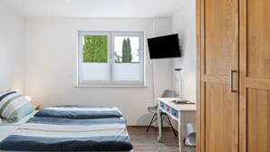 A bedroom with a bed, desk, chair, TV, and wardrobe. - Room 'Ruhiges Zimmer 2' with Shared Terrace, Wi-Fi and Air Conditioning (Wartenberg)