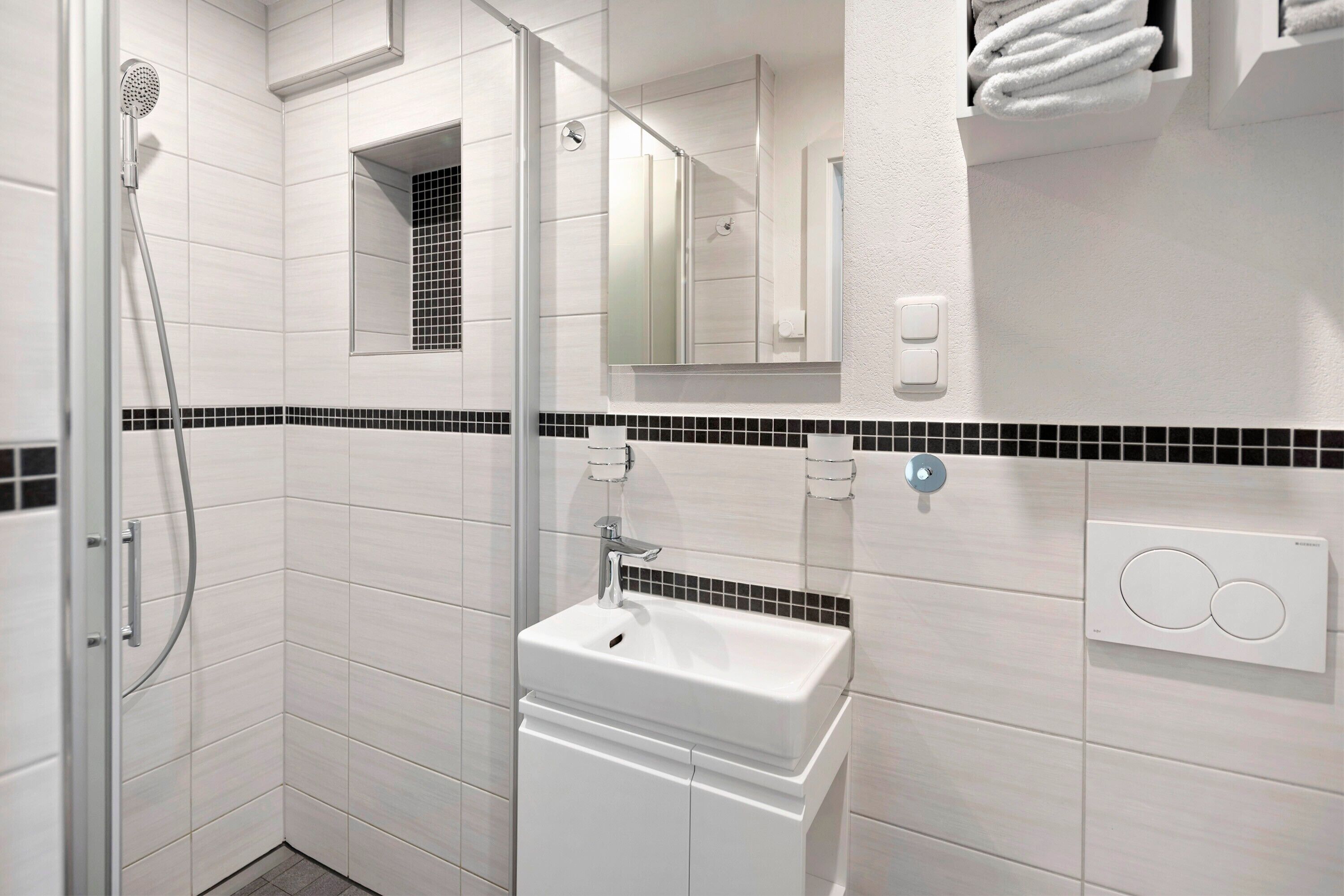 A modern bathroom with a shower, sink, and towel rack.
