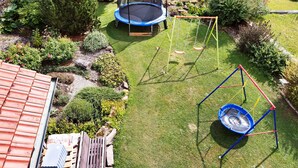 A backyard with a trampoline, swing set, and a small garden area. - Room 'Ruhiges Zimmer 2' with Shared Terrace, Wi-Fi and Air Conditioning (Wartenberg)