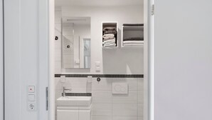 A modern bathroom with a white sink, toilet, and a mirror above the sink. There are two towel racks with folded towels. - Room 'Ruhiges Zimmer 2' with Shared Terrace, Wi-Fi and Air Conditioning (Wartenberg)