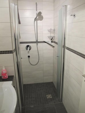 A small, tiled bathroom with a shower, a toilet, and a sink.