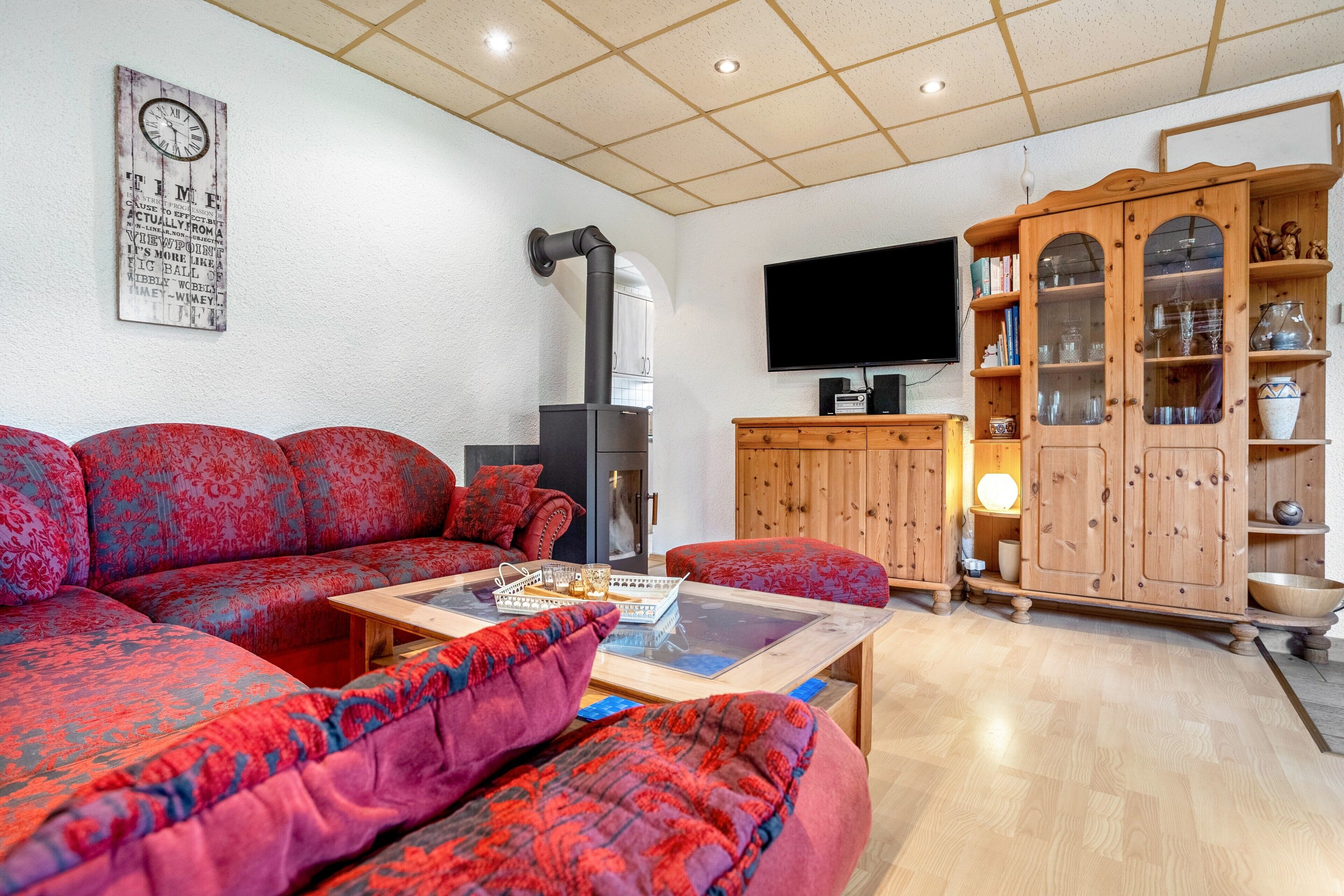 Ein Wohnzimmer mit einer Eckcouch, einem Holzschrank mit Glastüren, einem Flachbildfernseher und einem Kamin.