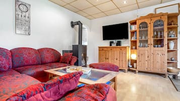 Un soggiorno con un divano componibile, un mobile contenitore in legno con vetrate, una TV a schermo piatto e un camino.