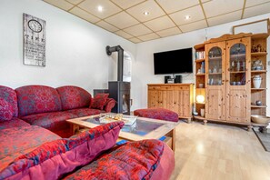 Een woonkamer met een hoekbank, een houten kast met glazen deuren, een flatscreentelevisie en een open haard.