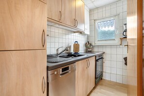 Cocina con armarios de madera, lavavajillas Bosch, un lavamanos y una ventana con vistas.