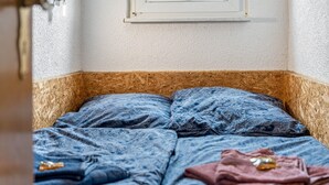 Une pièce avec un lit, une fenêtre et un luminaire fixé au mur.