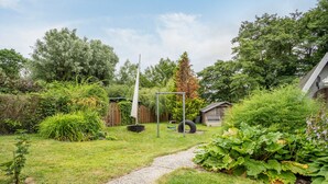 Un jardin avec un chemin de gravier, une balançoire et un petit abri de jardin.