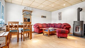 Un salon confortable avec un canapé, des fauteuils, une table, une cheminée et un miroir.