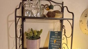 Een metalen schap met decoratieve objecten, waaronder een potplant, een beeldje van een eend en een ingelijst boek.