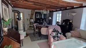 Una sala de estar acogedora con techo de madera, un comedor con mesa y sillas, y una cocina al fondo.