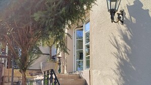 Una escalera de piedra que lleva a un edificio con un muro texturizado y una barandilla de metal.