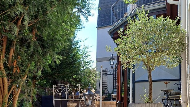 Un patio con mobiliario de mimbre, una maceta grande y un edificio con balcón.