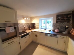 Eine Küche mit Backofen, Spüle und Fenster.