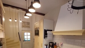 A kitchen with wooden cabinets, a black stove, a coffee maker, and hanging pendant lights. - Apartment 'Weinbergsblick' with Private Terrace, Private Garden and Balcony (Geisenheim)