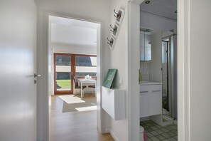 Un pasillo que conduce a un comedor con vistas al exterior, una cocina con un fregadero y armarios, y una puerta a un baño.