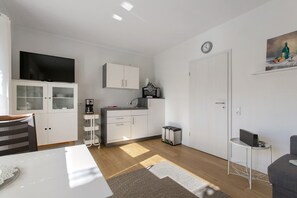 A modern kitchen with white cabinets, a microwave, and a coffee machine.