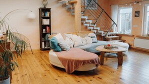 Una sala de estar moderna con piso de madera, un sofá, una mesa de centro, una estantería y una escalera.