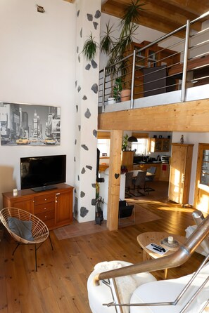 A spacious living area with a television, wooden furniture, a dining table, and a staircase leading to an upper level. - Holiday Home 'Das Blaue Haus Am Rothaarsteig' with Private Terrace, Private Garden and Wi-Fi (Kirchhundem)