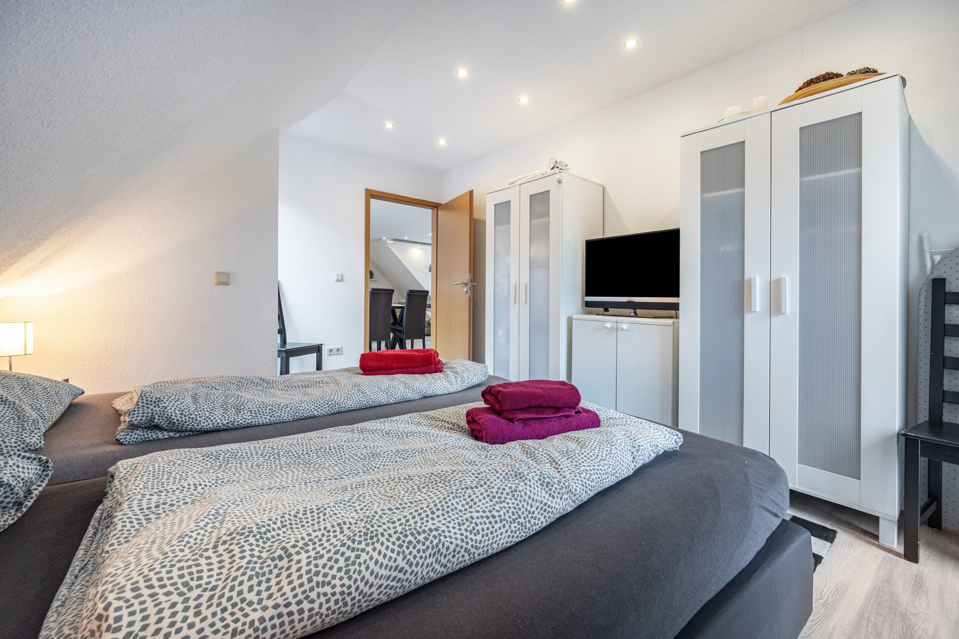 Ein Hotelzimmer mit zwei Betten, einem Fernseher, einem Kleiderschrank und einem Schreibtisch.