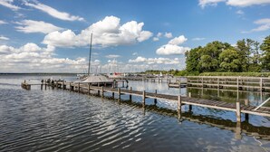 Un port de plaisance avec des bateaux amarrés, une jetée en bois et une zone herbeuse avec des arbres.