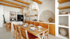 Una cucina moderna con travi in legno, mobili bianchi e un'area pranzo con tavolo e sedie di legno.