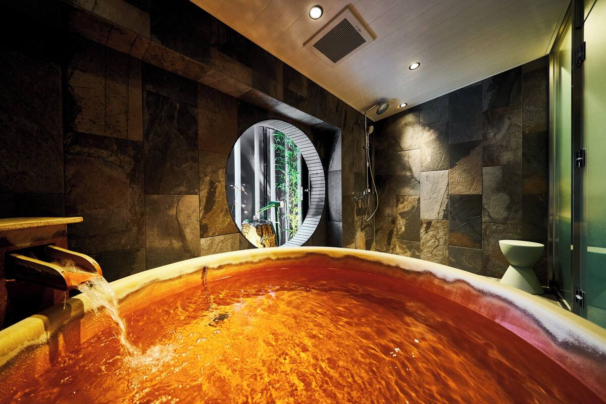 Una stanza spa con una grande vasca idromassaggio, pareti in pietra e una finestra vista.