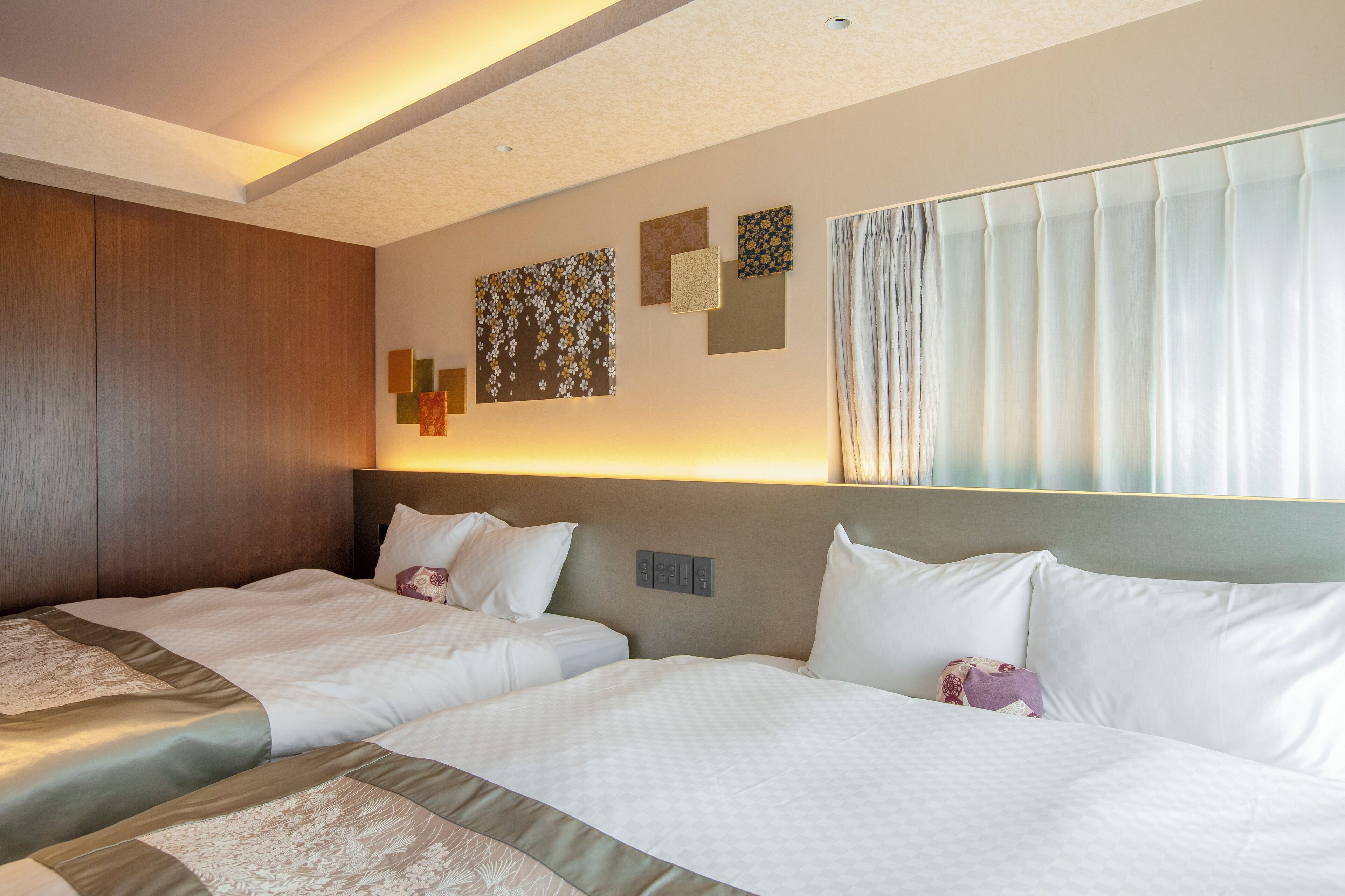 A hotel room with two beds, a wooden wardrobe, and artwork on the walls.