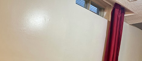 Una habitación con un escritorio de madera, sillas negras, una cortina roja y una escalera.