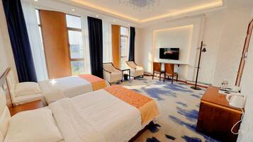 A hotel room with two beds, a TV, a desk, and a chair.