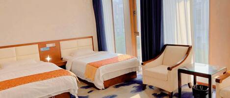 Ein Hotelzimmer mit zwei Betten, einem Sessel, einem kleinen Tisch und einem Fenster mit Vorhängen.