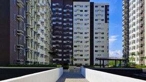 A modern apartment building with multiple floors, balconies, and a central courtyard with a stone pathway.