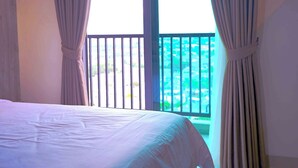 Habitación de hotel con cama y balcón con vista a una piscina.
