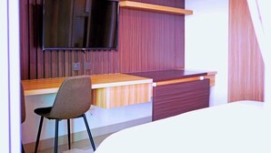 Una habitación moderna con un escritorio de madera, una silla, un televisor de pantalla plana montado en la pared y una puerta corredera.