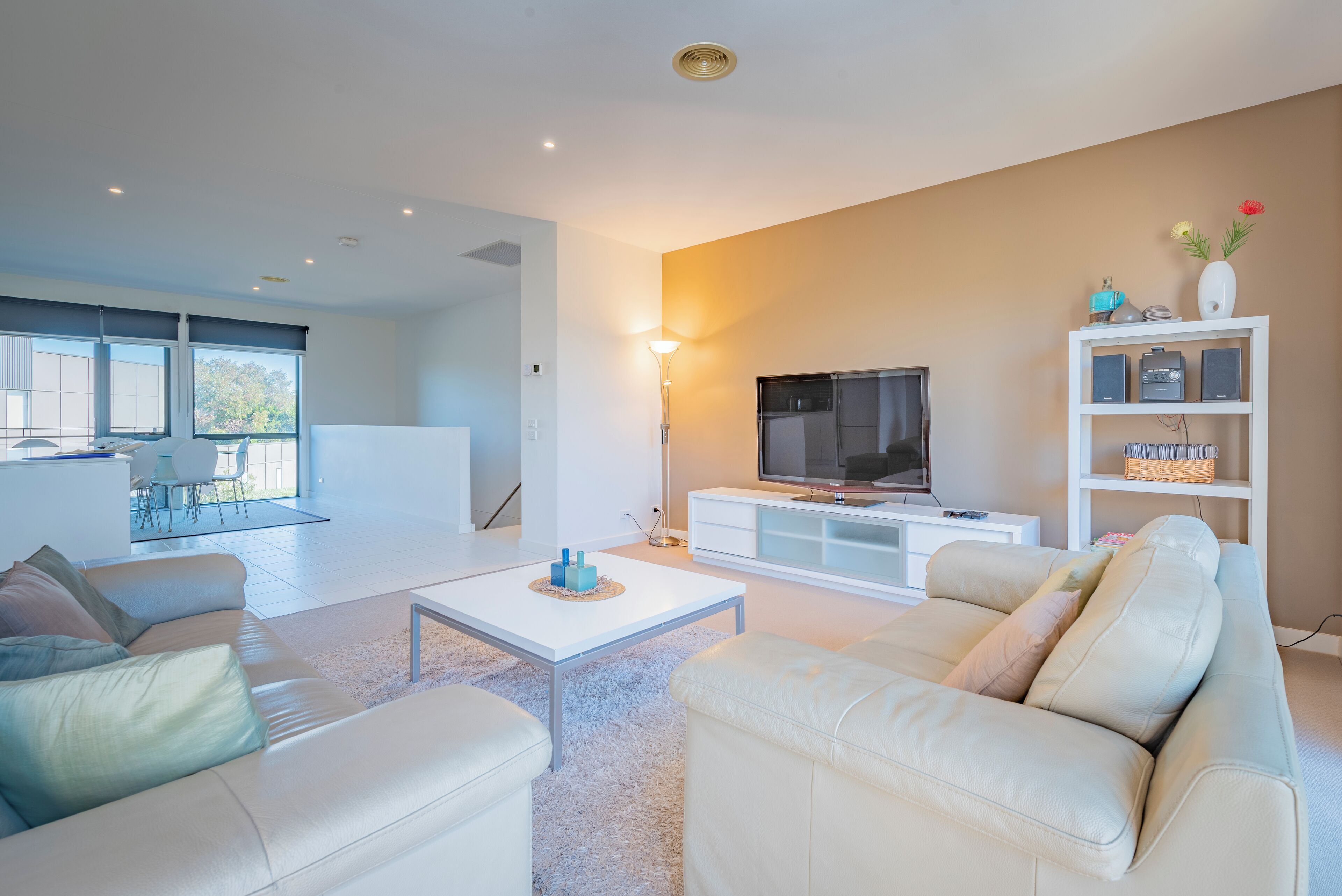 A modern living room with a sofa, coffee table, TV, and a bookshelf.