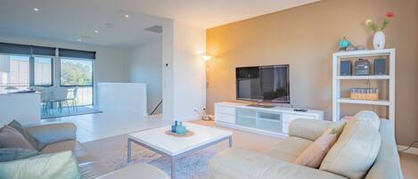 A modern living room with a sofa, coffee table, TV, and a bookshelf.