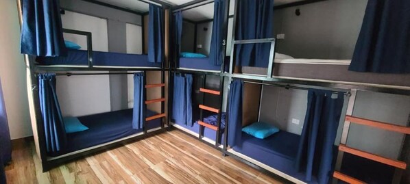 A bunk bed room with curtains, a ladder, and a wooden floor. - Travelero Hostel ans Tours (Santa Cruz)