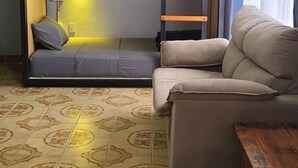 Una habitación con literas, un sofá, un banco de madera y baldosas de suelo estampadas.