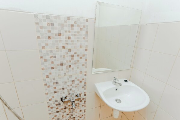 Une salle de bain avec une paroi de douche carrelée, un lavabo et un miroir.