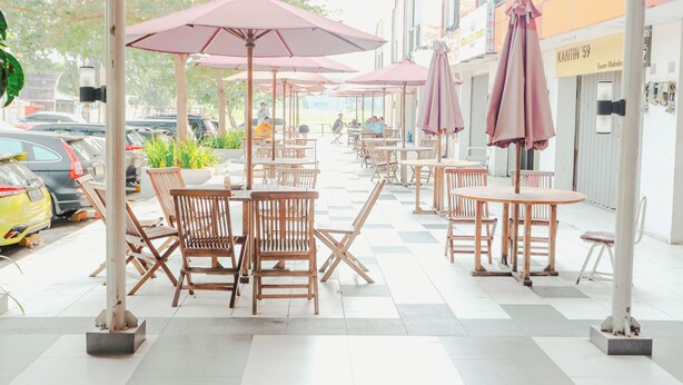 Un café con terraza, que incluye mesas y sillas, y sombrillas.