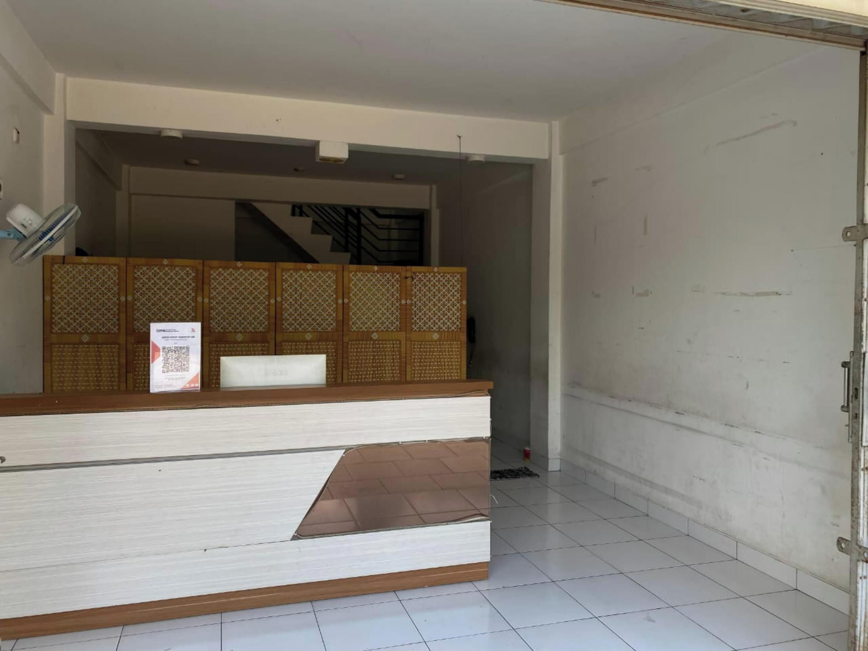 Un comptoir d’accueil avec un panneau décoratif, une chaise blanche et une enseigne.