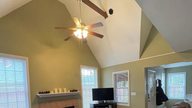 Ein Wohnzimmer mit Kamin, Fernseher und Deckenventilator.