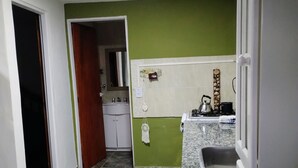 Una cocina con pared verde, un lavamanos, una estufa y un armario.