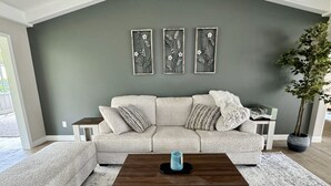 A living room with a grey sofa, a wooden coffee table, and a potted plant. - Newly remodeled 3 BR house, 5 min from WEC and by golf course. Dogs allowed (Ocala)