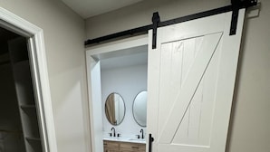 A hallway leading to a bathroom with a white door, a mirror, and a sink. - Newly remodeled 3 BR house, 5 min from WEC and by golf course. Dogs allowed (Ocala)