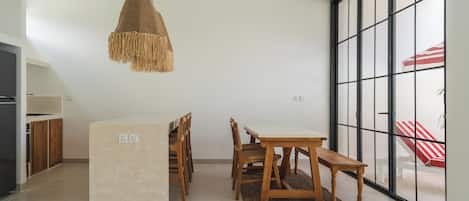 Una cocina moderna con armarios de madera, una isla central y un comedor con mesa y sillas.