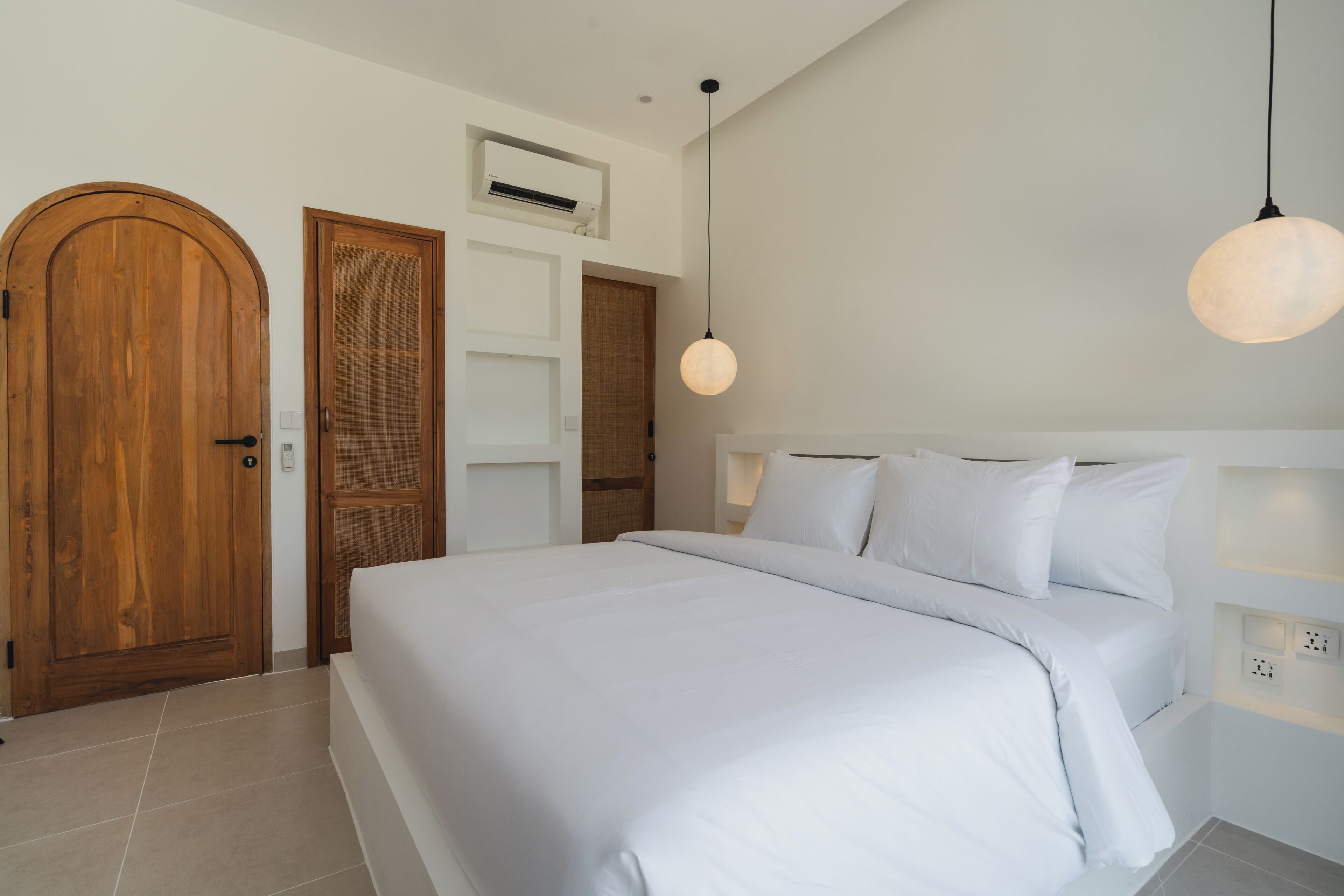 Una camera da letto moderna con un letto grande, porte in legno e un condizionatore d'aria a soffitto.