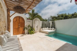 A pool area with a wooden door, a white wall, and a cactus garden. - Villa Makai by Alfred in Bali (Canggu)