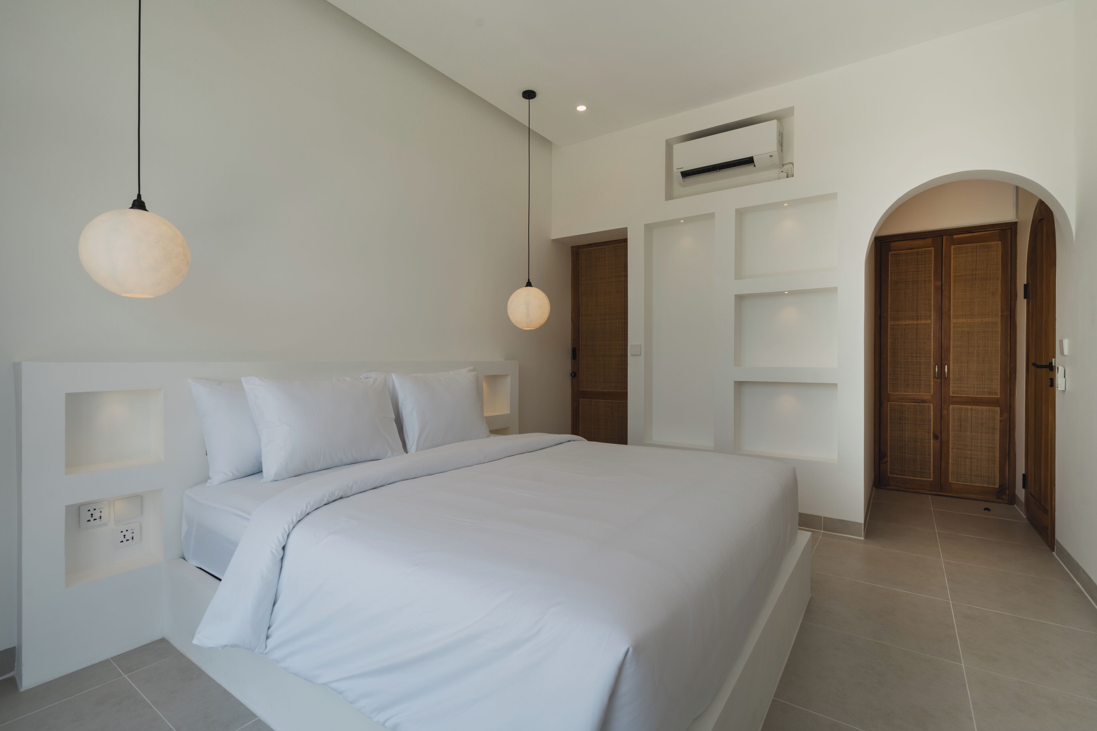 A modern bedroom with a large bed, white bedding, and a hanging light fixture.